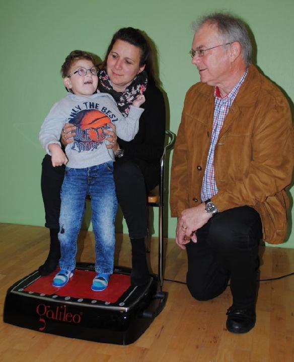 Das Foto zeigt den aufgeweckten Henry auf seinem 'Galileo-Therapiegerät' mit Mama Sandy und Klaus Port ( Bildrechte: Jürgen Becker)