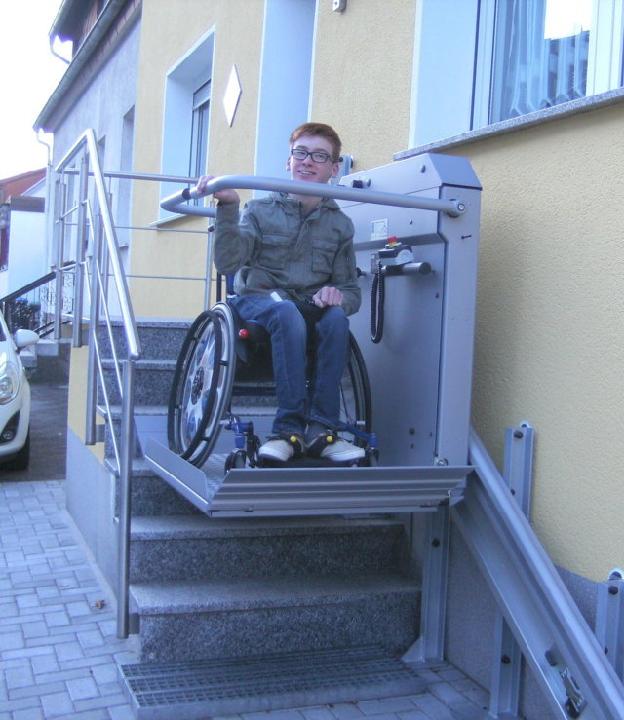 Stolz demonstriert der aufgeweckte Lars die Funktionalität des neuen Rollstuhl-Schrägaufzuges am Hauseingang, mit dem er ein gutes Stück an Eigenständigkeit gewinnt und nun ohne Hilfe ins Haus oder aus dem Haus gelangen kann (Bildrechte: Klaus Port)